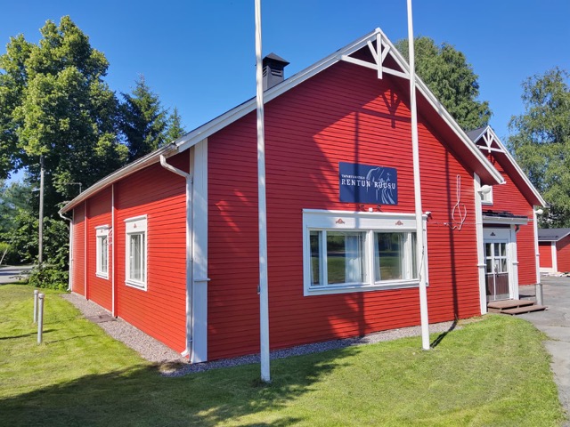 Rentun Ruusun punainen puutalo kesäpäivänä pihalta kuvattuna